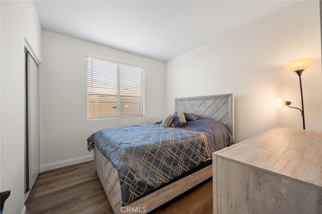 bedroom featuring a closet, dark wood-style flooring, and baseboards