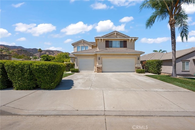 view of front of home featuring concrete driveway, a mountain view, an attached garage, and stucco siding