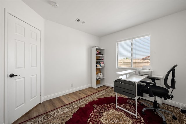 office area with wood finished floors, visible vents, and baseboards