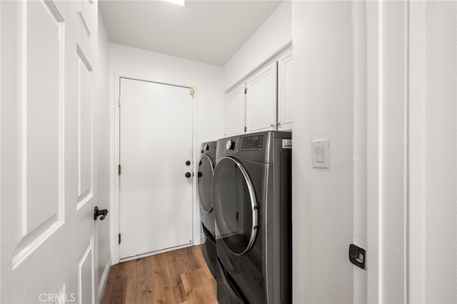 clothes washing area with washer and dryer, cabinet space, and light wood-style flooring