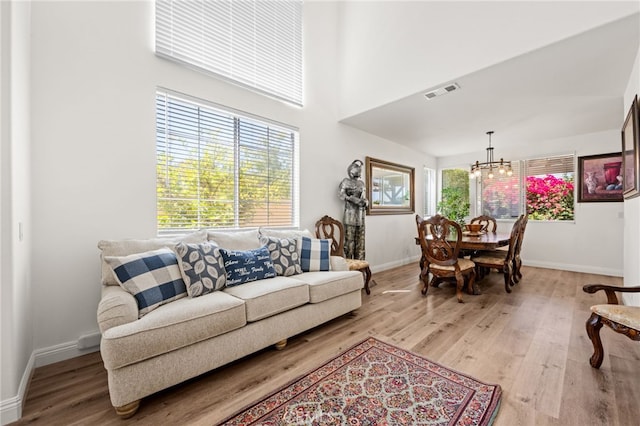 living area featuring an inviting chandelier, baseboards, visible vents, and wood finished floors