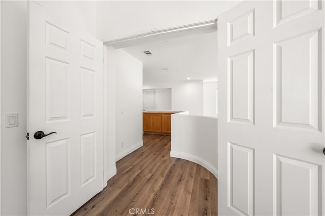 hall featuring visible vents, dark wood finished floors, and baseboards