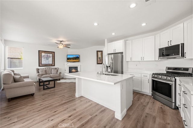 kitchen featuring light countertops, appliances with stainless steel finishes, open floor plan, white cabinetry, and a sink