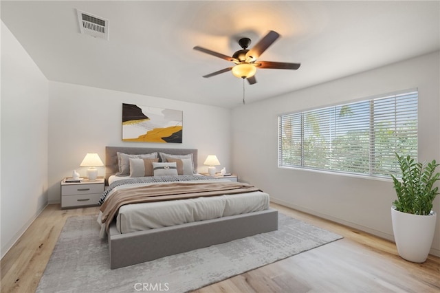 bedroom with light wood-style flooring, visible vents, ceiling fan, and baseboards