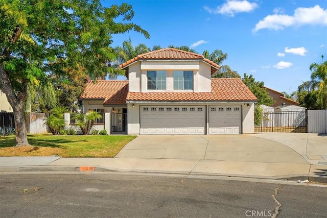 mediterranean / spanish home featuring a front yard, a tile roof, fence, and stucco siding