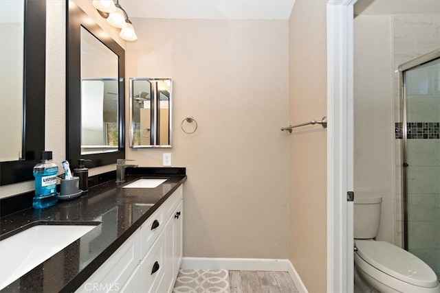 bathroom with wood-type flooring, vanity, toilet, and a shower with door