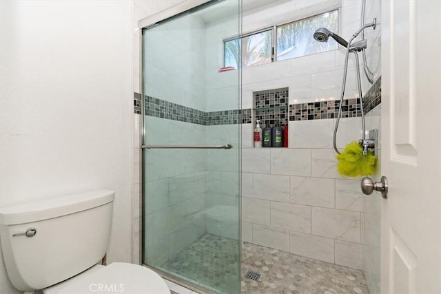 bathroom featuring toilet and a shower stall