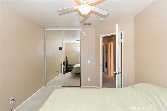 bedroom with ceiling fan, a closet, and light carpet