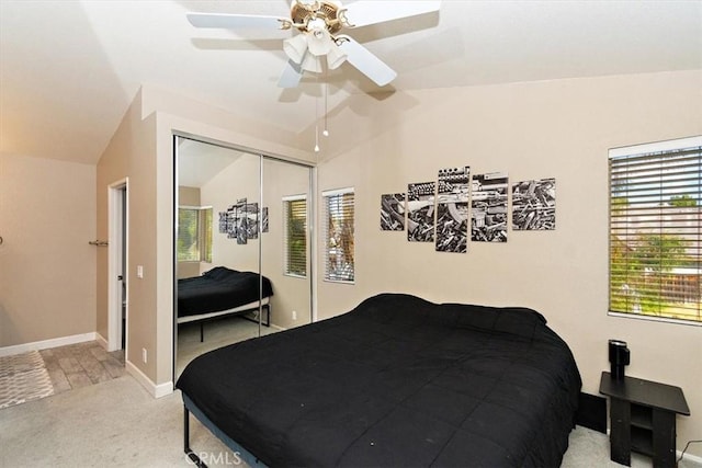 bedroom with baseboards, light colored carpet, lofted ceiling, ceiling fan, and a closet