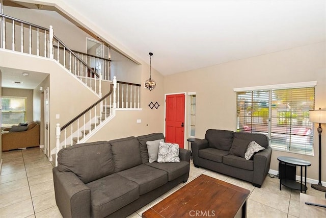 living area featuring high vaulted ceiling, light tile patterned flooring, baseboards, and stairs