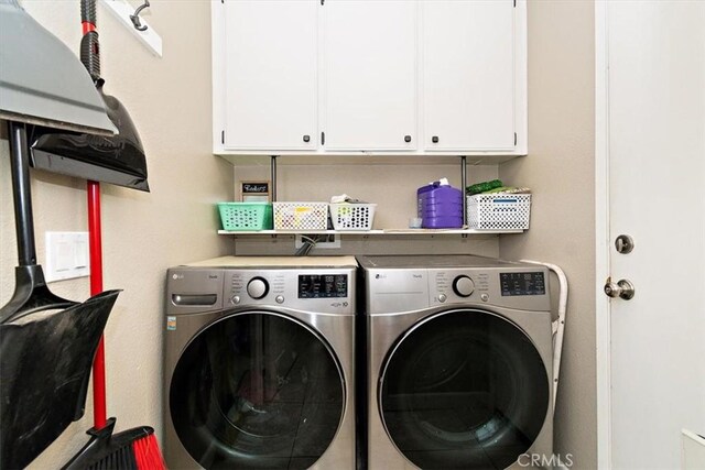 washroom with washing machine and clothes dryer and cabinets