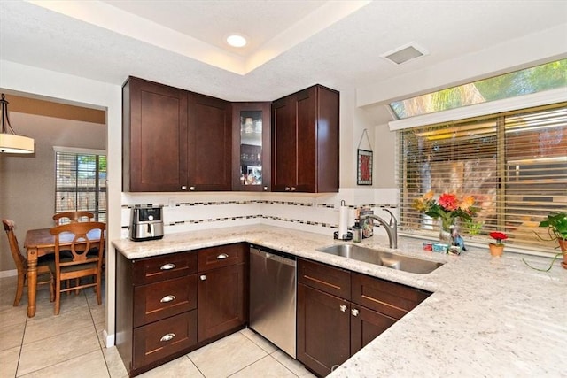 kitchen with dark brown cabinetry, decorative backsplash, dishwasher, light stone counters, and a sink