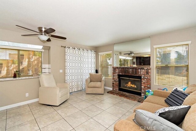 tiled living room featuring a fireplace and ceiling fan