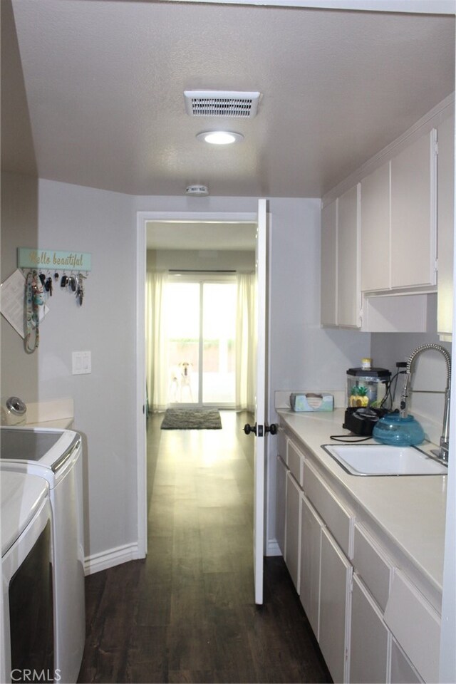 kitchen featuring washer and clothes dryer, sink, dark hardwood / wood-style flooring, and white cabinets