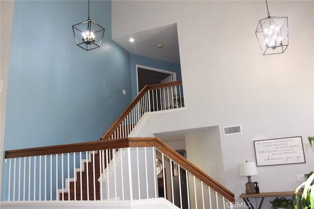 stairs featuring an inviting chandelier and a towering ceiling