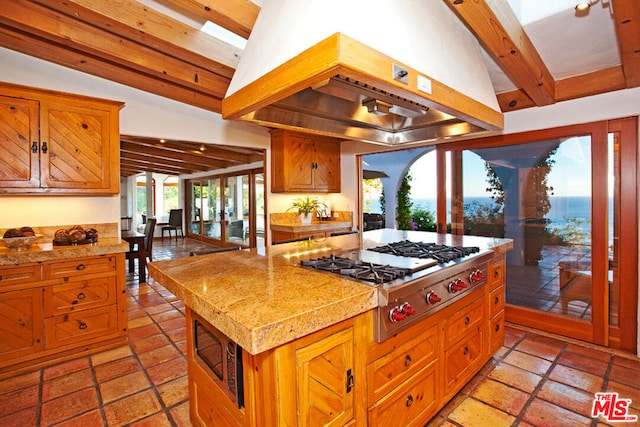 kitchen featuring custom range hood, a center island, lofted ceiling with beams, and stainless steel appliances