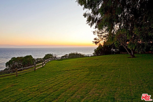 yard at dusk featuring a water view