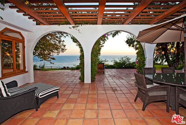 patio terrace at dusk with a water view and a pergola