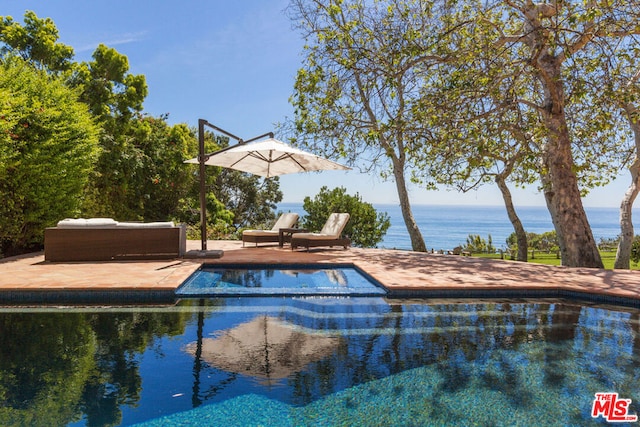 view of swimming pool featuring a patio and a water view