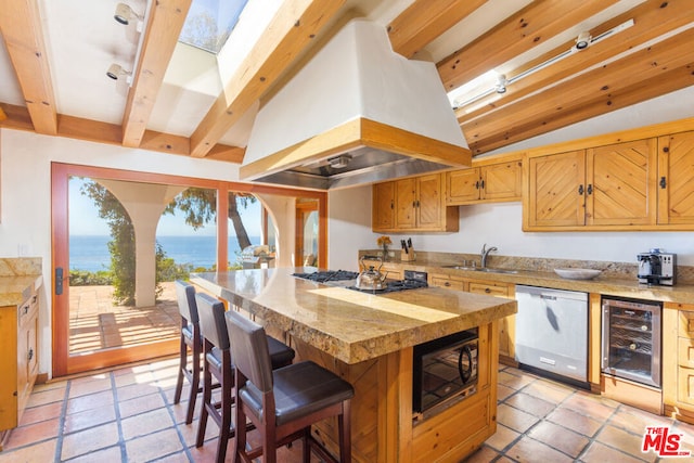 kitchen with custom exhaust hood, beverage cooler, lofted ceiling with skylight, stainless steel appliances, and a water view