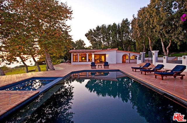 pool at dusk featuring a patio