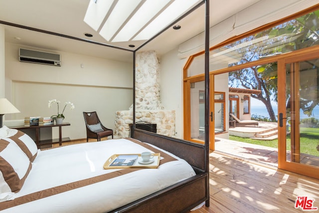 bedroom featuring wood-type flooring, a fireplace, french doors, an AC wall unit, and access to exterior