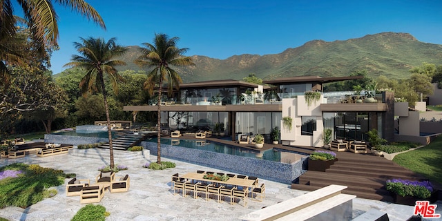 rear view of property with a swimming pool with hot tub, a mountain view, and a patio