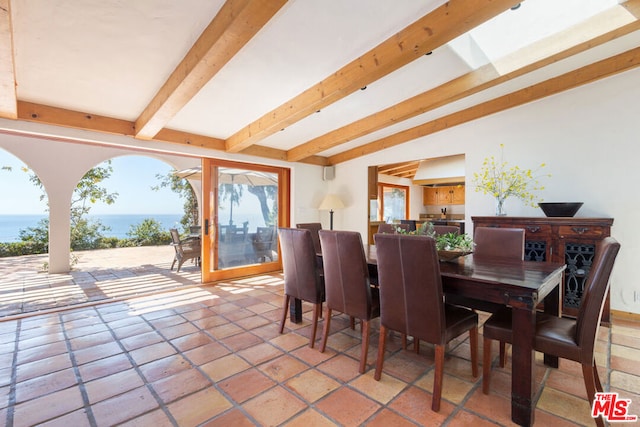 dining space with beamed ceiling and a water view