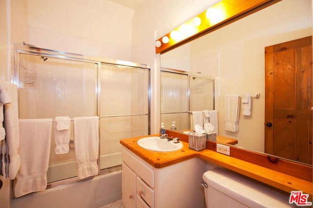 full bathroom featuring vanity, combined bath / shower with glass door, and toilet