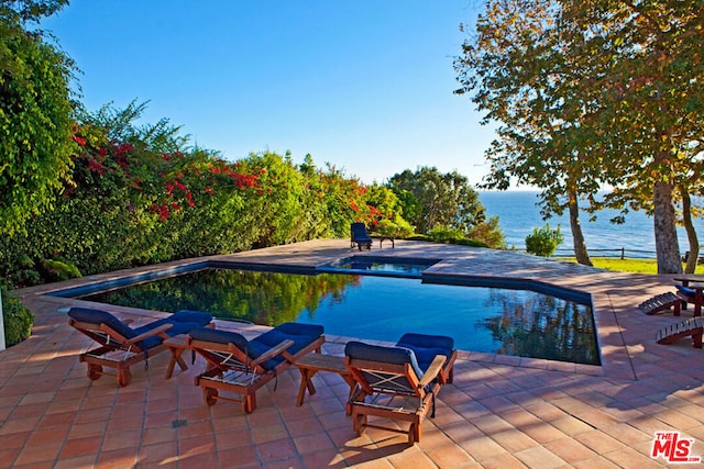 view of pool with a water view and a patio