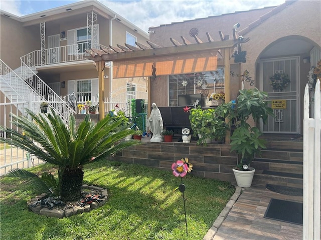 rear view of house featuring a pergola, stairs, and stucco siding