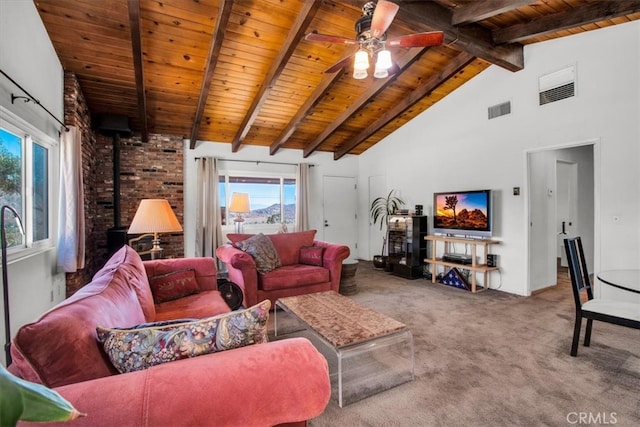 carpeted living room with a healthy amount of sunlight, beamed ceiling, wood ceiling, and a wood stove