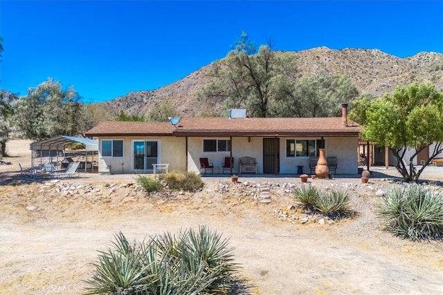 ranch-style house featuring a porch, a mountain view, and a carport