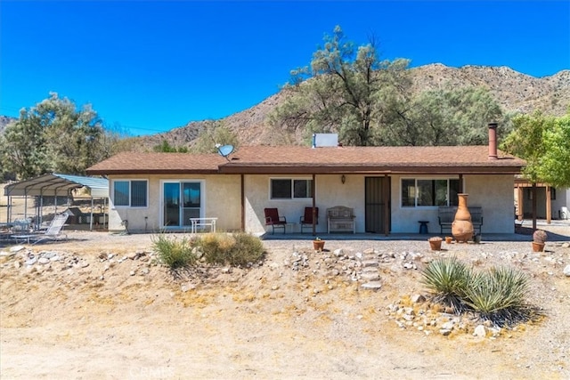 back of house with a carport and a mountain view