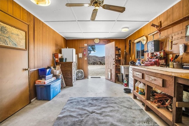 miscellaneous room featuring ceiling fan, a workshop area, and wood walls