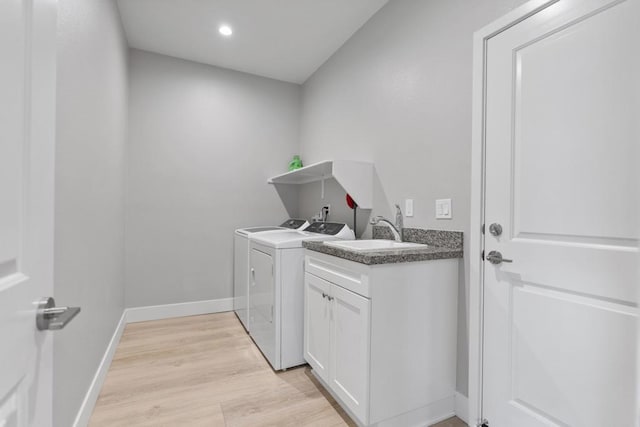 laundry area featuring cabinets, light hardwood / wood-style flooring, washing machine and clothes dryer, and sink