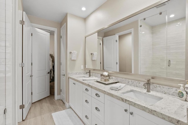 bathroom with hardwood / wood-style flooring, an enclosed shower, and vanity