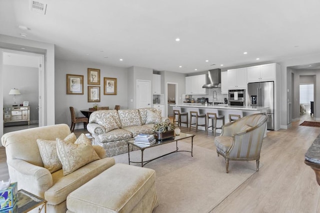 living room featuring sink and light hardwood / wood-style floors