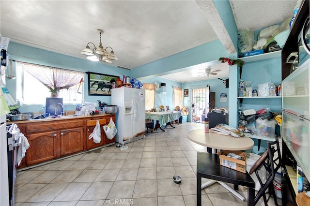 kitchen with ceiling fan with notable chandelier, light tile patterned flooring, white fridge with ice dispenser, and sink