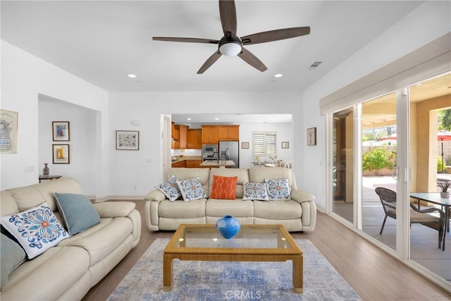 living room featuring ceiling fan and light hardwood / wood-style flooring