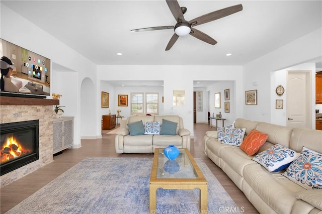 living room featuring ceiling fan, hardwood / wood-style floors, and a fireplace