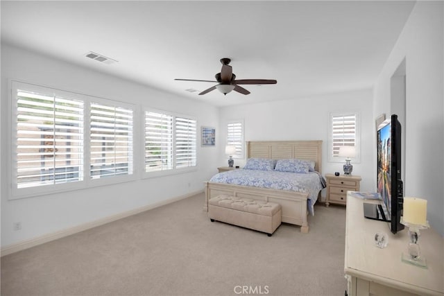 bedroom with ceiling fan, multiple windows, and light carpet