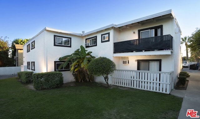 view of front of property featuring a balcony and a front lawn