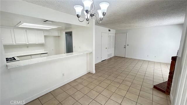 kitchen with white cabinets, light tile patterned flooring, a textured ceiling, decorative light fixtures, and a chandelier