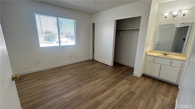 unfurnished bedroom featuring a textured ceiling, a closet, sink, and hardwood / wood-style floors