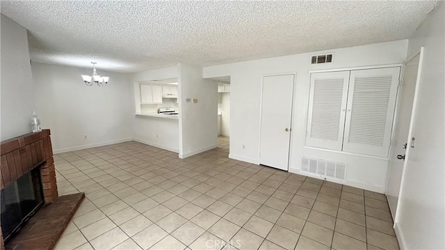 unfurnished living room with baseboards, a fireplace, visible vents, and a notable chandelier