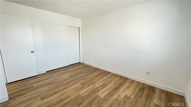 unfurnished bedroom with a closet, hardwood / wood-style floors, and a textured ceiling