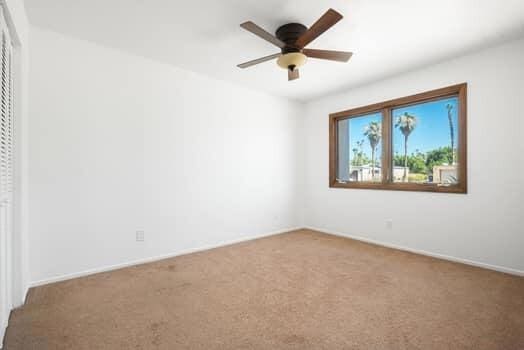 carpeted spare room featuring ceiling fan