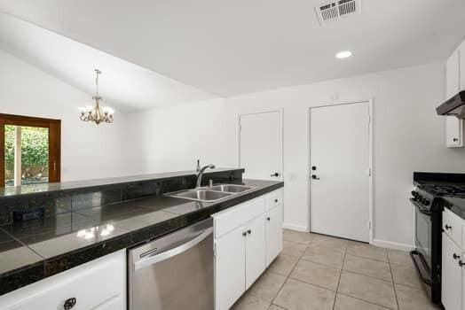 kitchen featuring dishwasher, sink, lofted ceiling, white cabinetry, and black range with gas stovetop