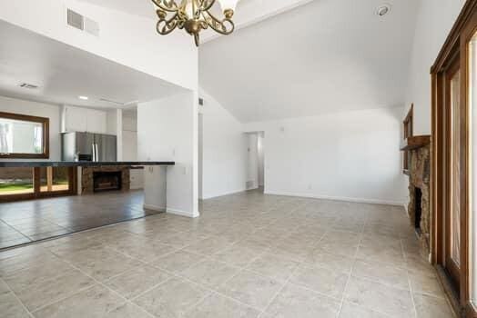 unfurnished living room featuring a notable chandelier and high vaulted ceiling